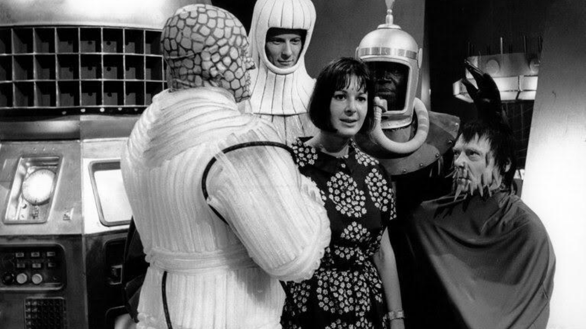 Verity Lambert, pictured on a sci-fi television set, with three actors around her, dressed as a variety of aliens.